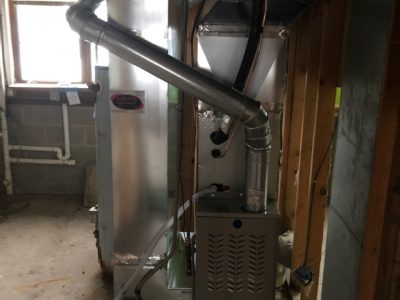 A view of the inside of a house with pipes and an air handler.