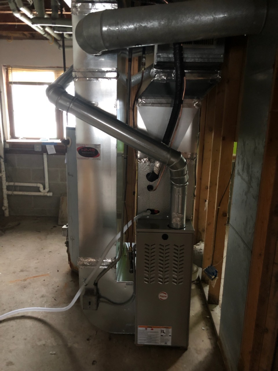A view of the inside of a house with pipes and an air handler.